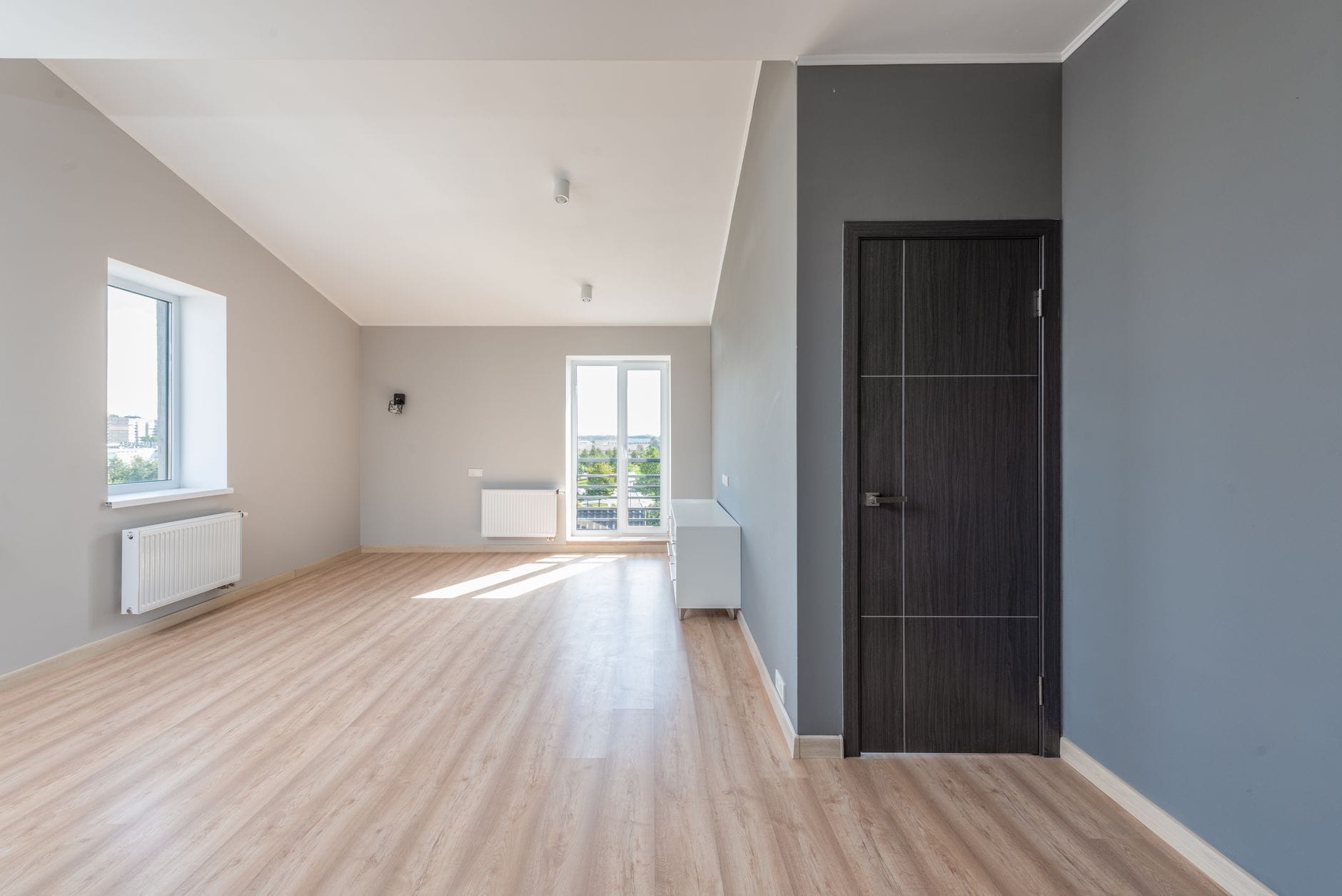 Jasny pusty salon z drewnianą podłogą i dużymi oknami bez listew Jasny pusty salon z drewnianą podłogą i dużymi oknami bez listew