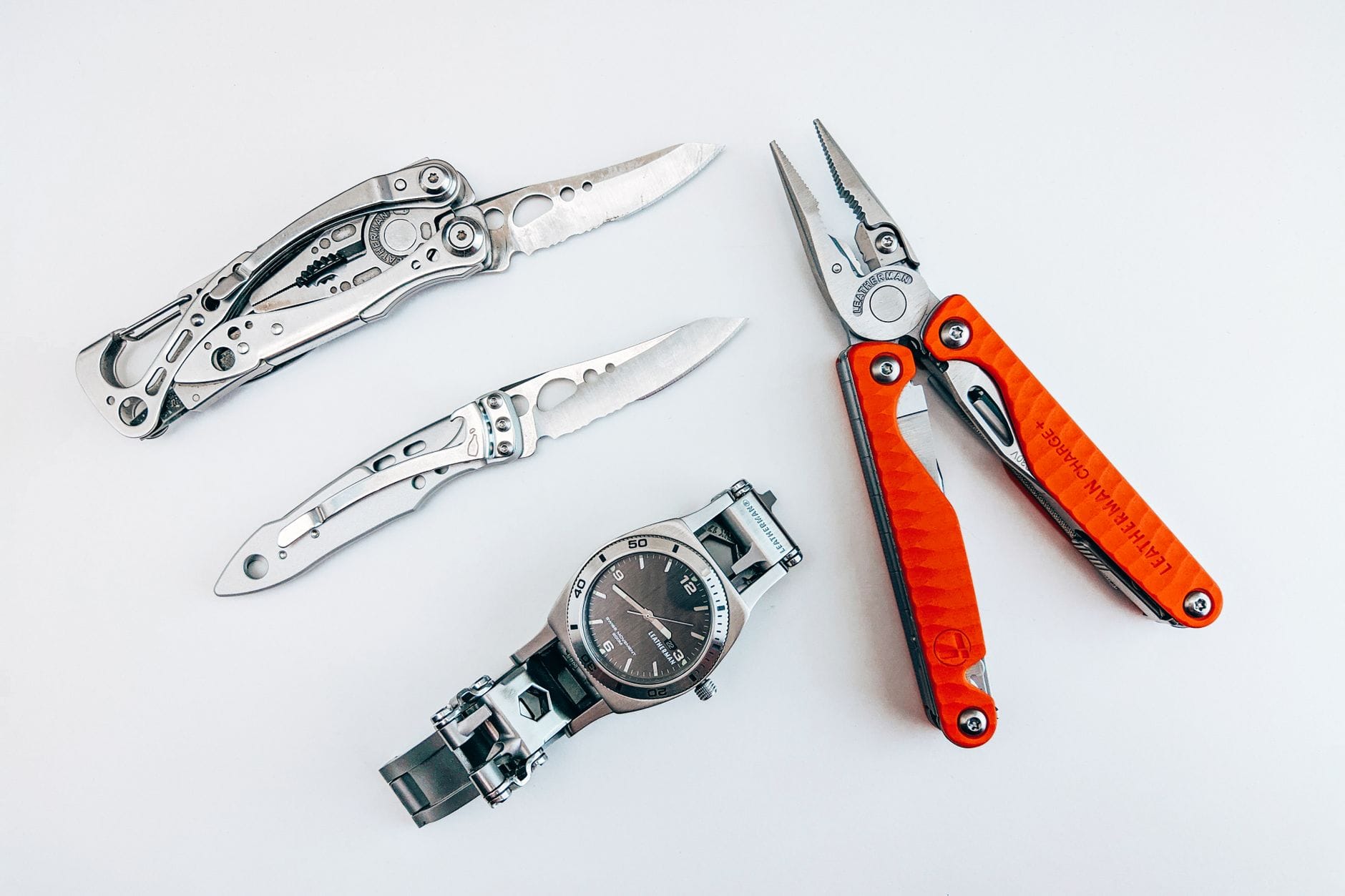 Multitool i zegarek rozłożone na białym tle jako akcesoria EDC