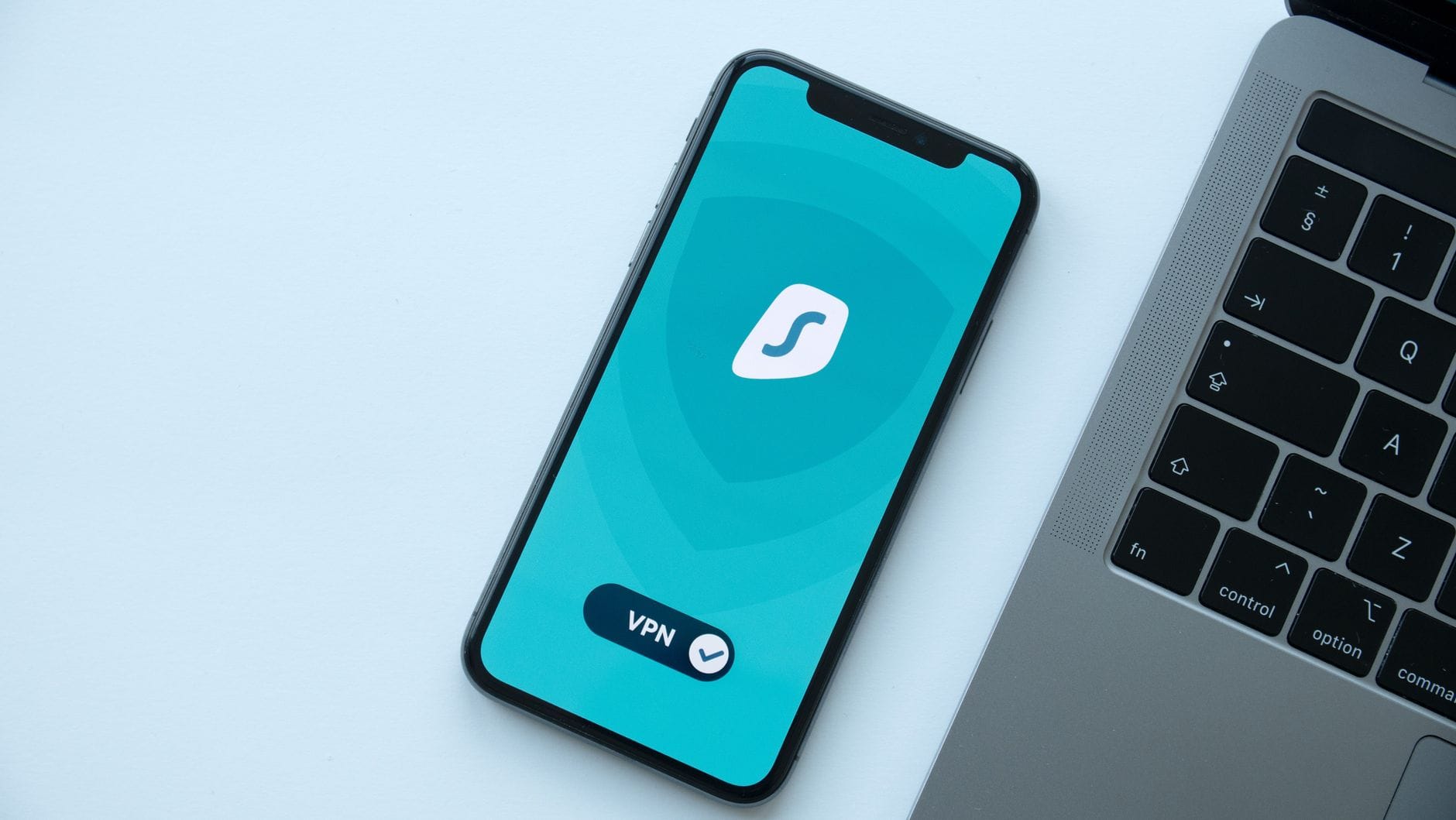 Smartfon z włączoną aplikacją VPN leżący obok laptopa na biurku