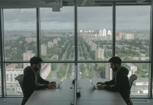 Dwaj specjaliści IT przy laptopach w biurze z widokiem na miasto