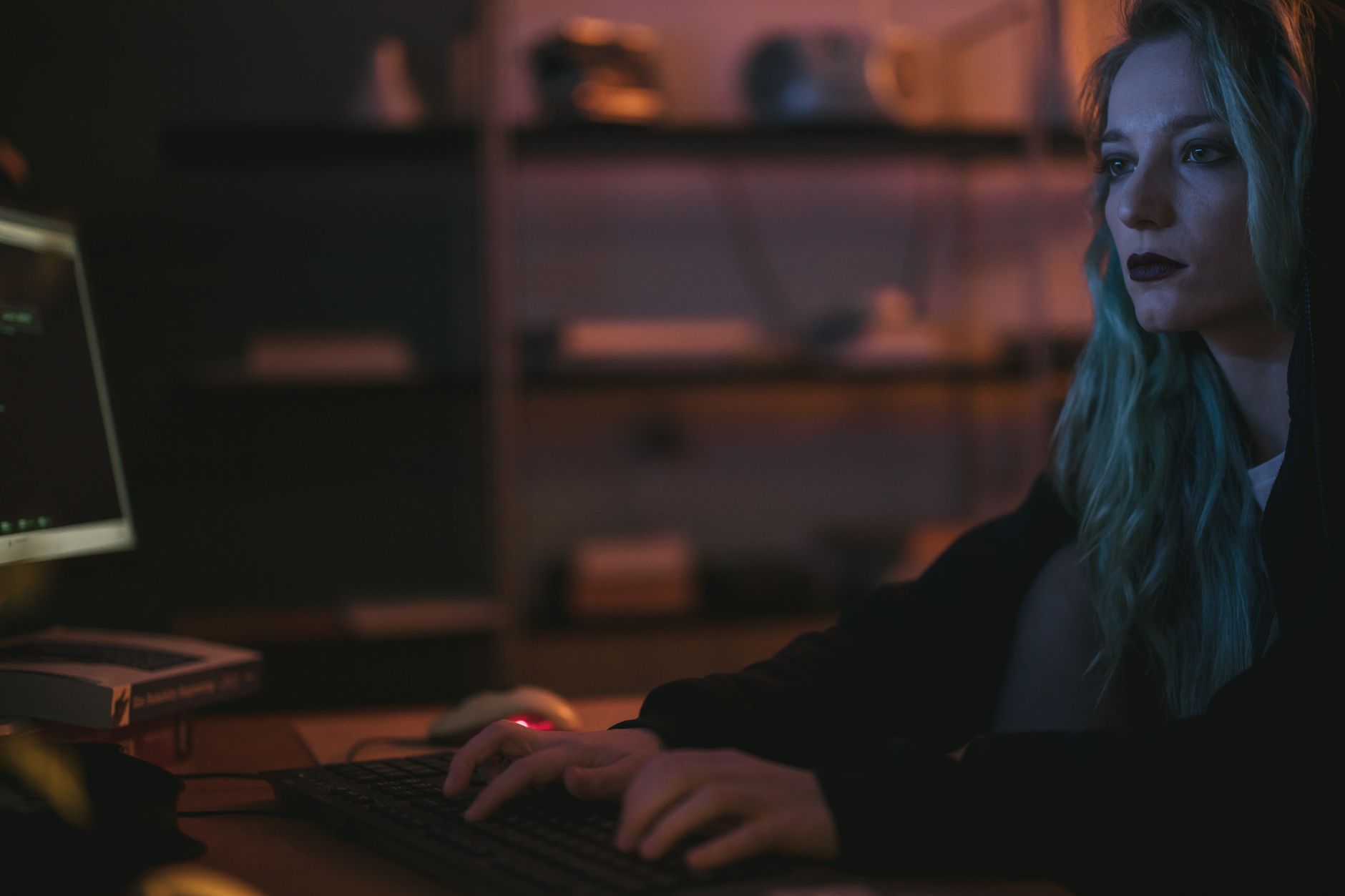 Kobieta z niebieskimi włosami pracuje przy komputerze nad cyberbezpieczeństwem